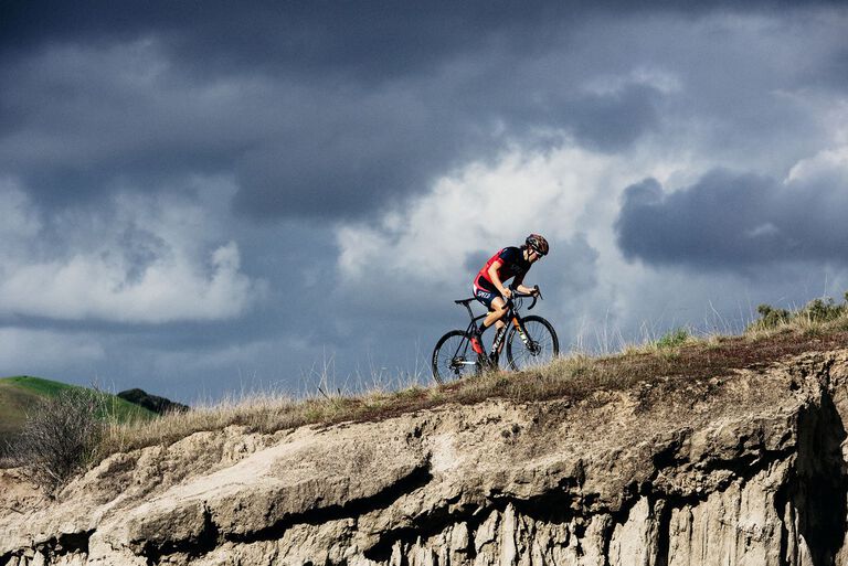 Biker climbing a hill with a storm in the background. 